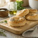 Golden and soft gluten-free bagels with sesame and poppy seeds on a wooden board.