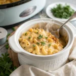 Creamy crockpot mac and cheese in a white slow cooker with melted cheddar cheese